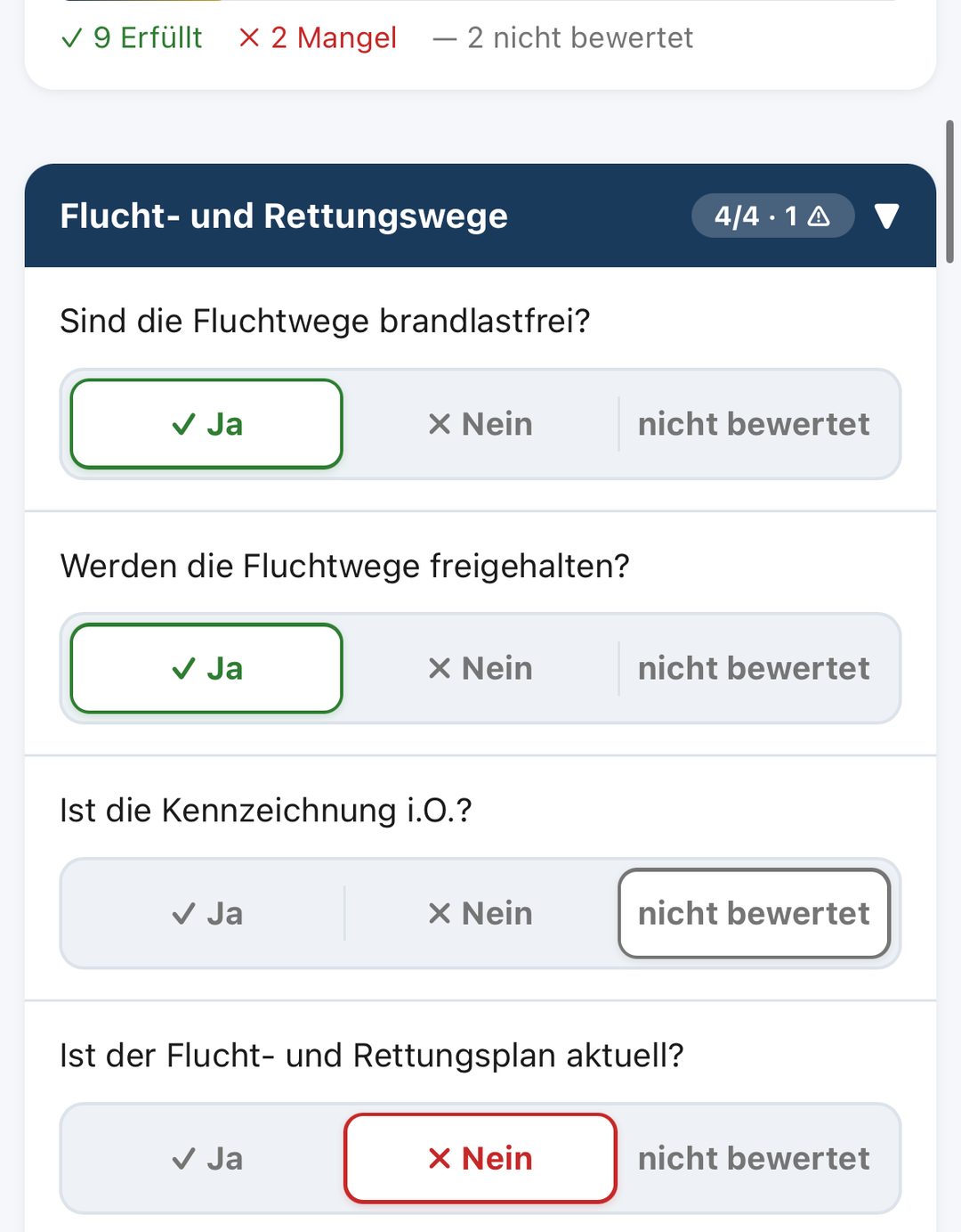 VigilOS Brandschutz Begehung auf dem iPhone: Fortschritt mit 9 erfüllten Punkten, 2 Mängeln und 2 nicht bewerteten, darunter die Kategorie Flucht- und Rettungswege mit vier Prüfpunkten, „Ist der Flucht- und Rettungsplan aktuell?“ rot mit „Nein“ bewertet